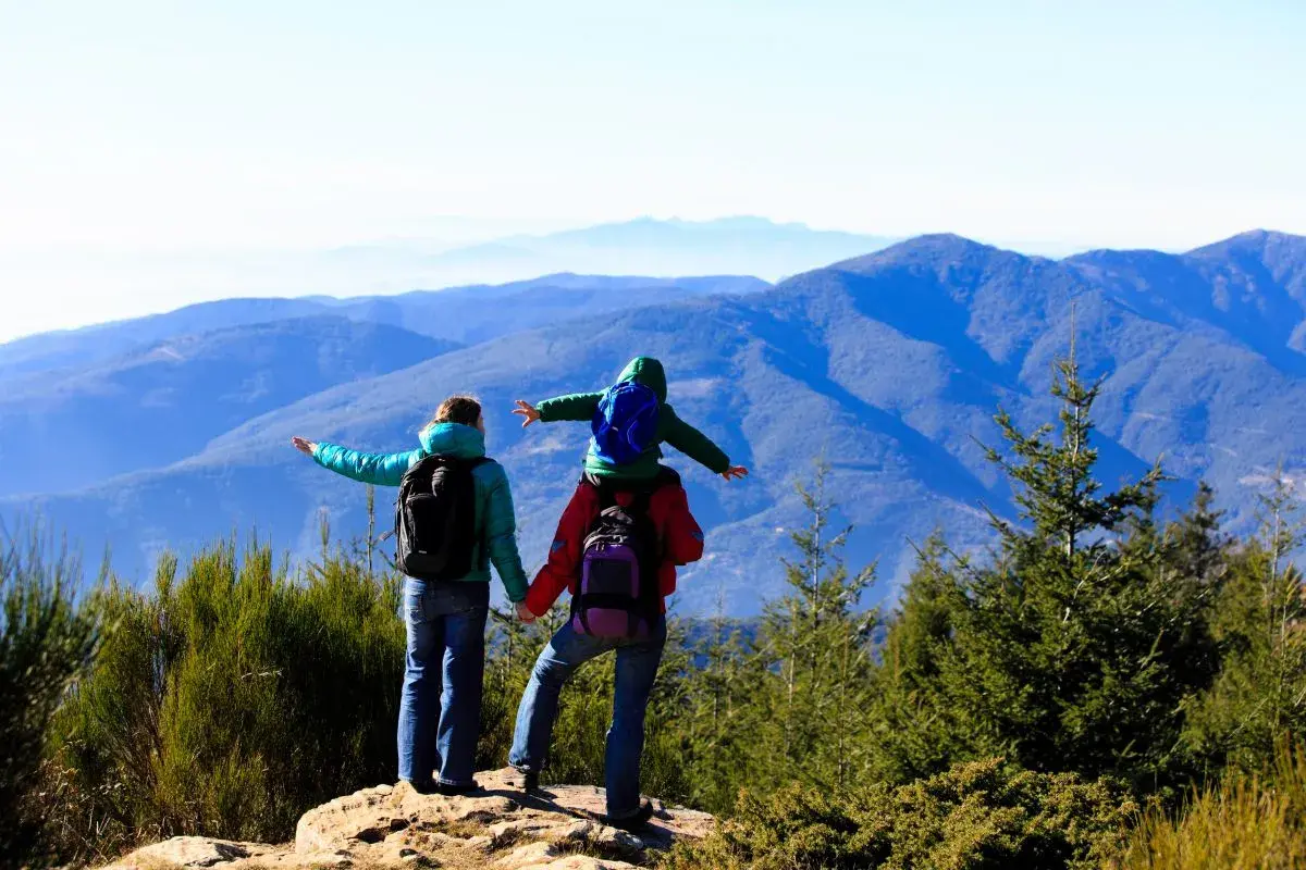 Familia disfrutando de las rutes montseny, con un niño a hombros, contemplando el paisaje montañoso.