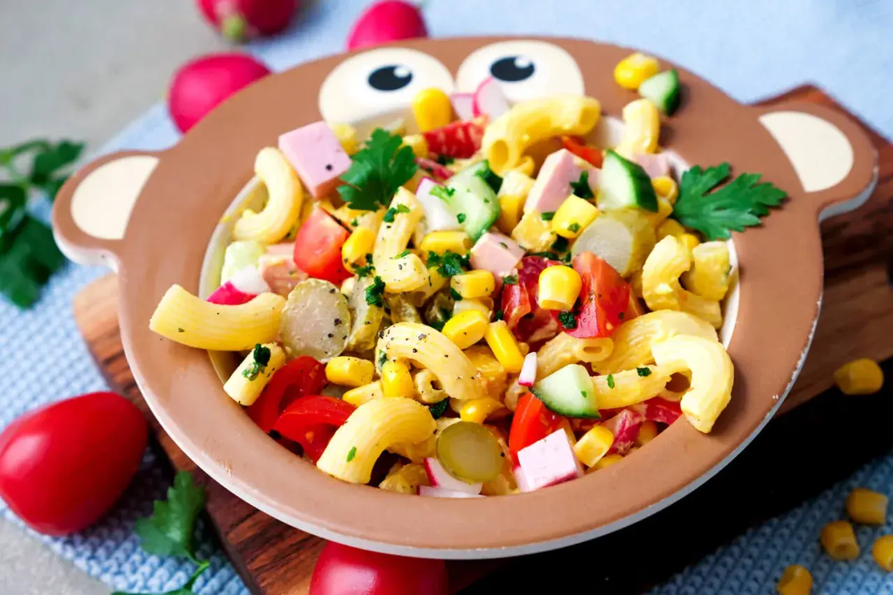 Bunter Nudelsalat mit Mais, Tomaten und Gurken in einem Affen-Teller – perfekt für Kinder!