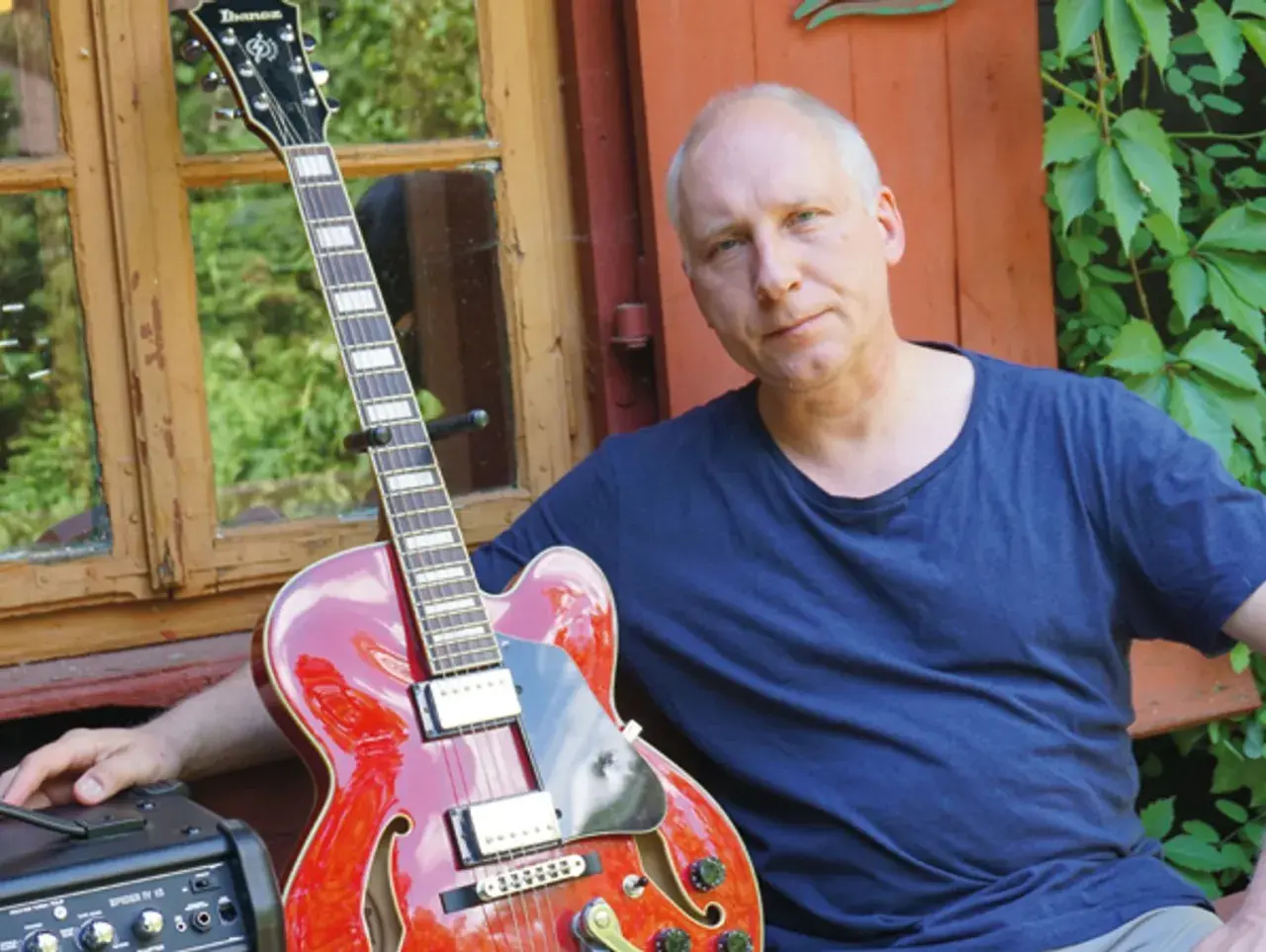 Kuba Sienkiewicz z zespołem przygotowuje się do koncertu. Czerwona gitara i wzrok pełen skupienia.