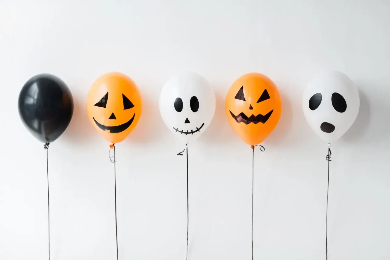 Fünf Ballons für Halloween basteln: ein schwarzer, zwei Kürbis-Ballons und zwei Geister-Ballons.