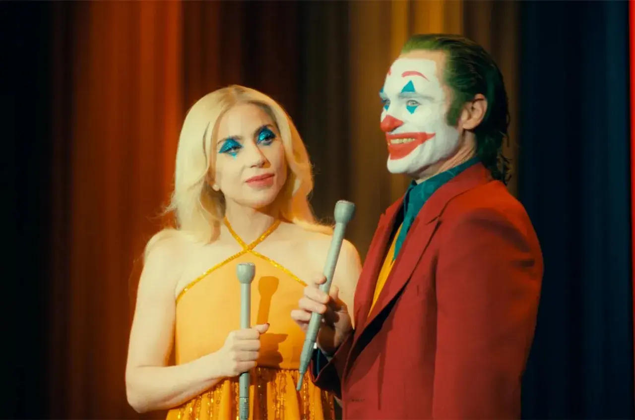 Joker e Harley Quinn, con il trucco da clown, cantano sul palco. Una scena iconica del finale di Joker.