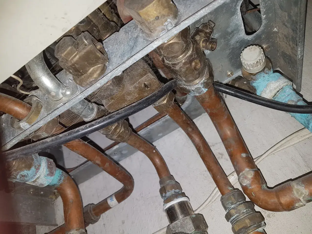 Instalacja pieca gazowego Vaillant z miedzianymi rurami. Widoczne przyłącza i zawory, być może problem ze słabym ciśnieniem ciepłej wody.