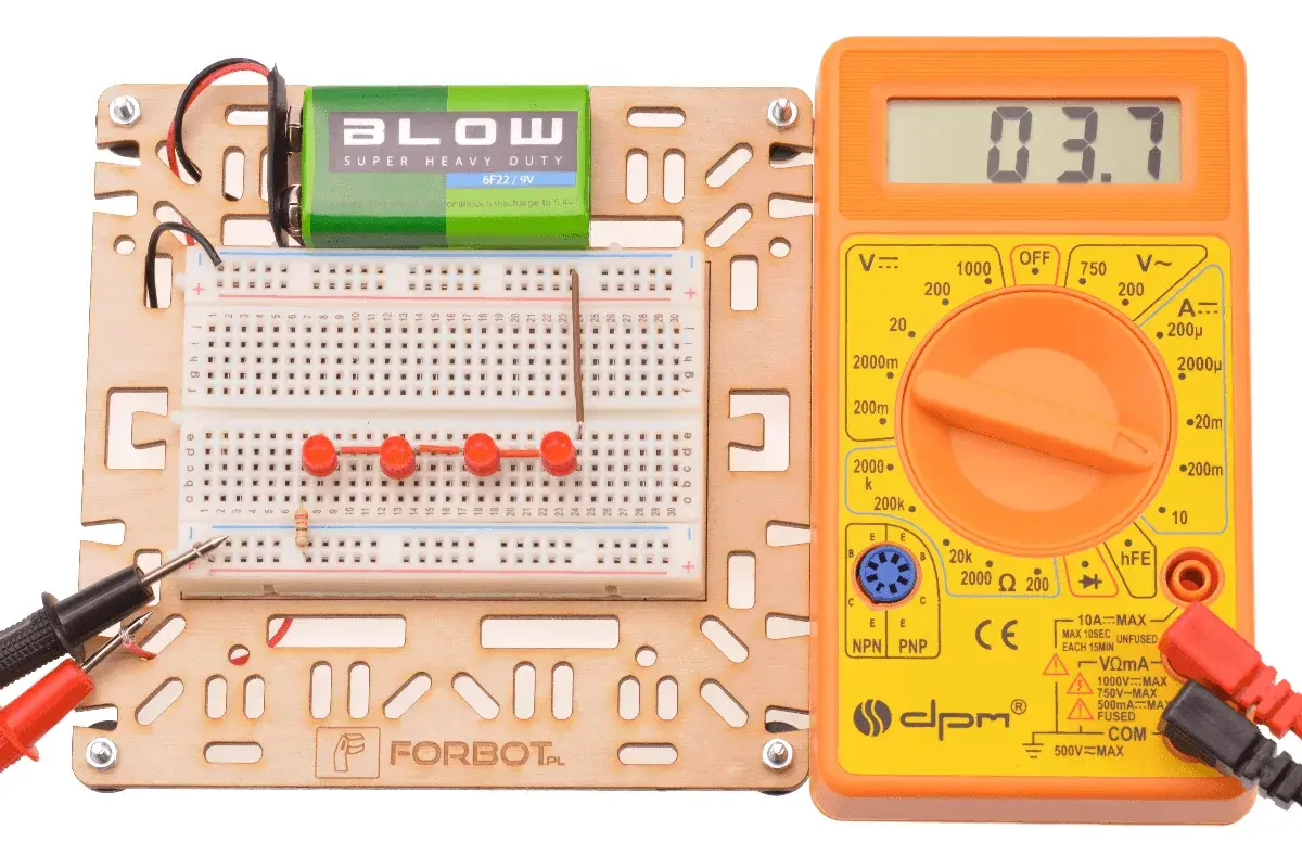Zestaw do eksperymentów z elektroniką: płytka stykowa, bateria 9V, multimetr i rezystor.