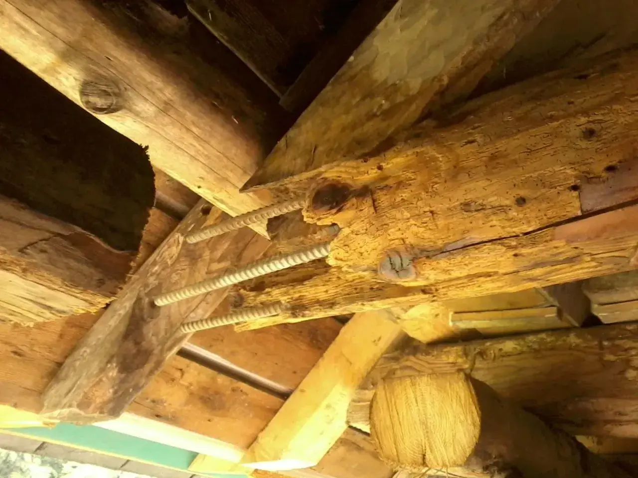 Poutre en bois vermoulue, soutenue par des tiges filetées. Le prix pour changer une poutre pourrie est une préoccupation majeure pour la rénovation.