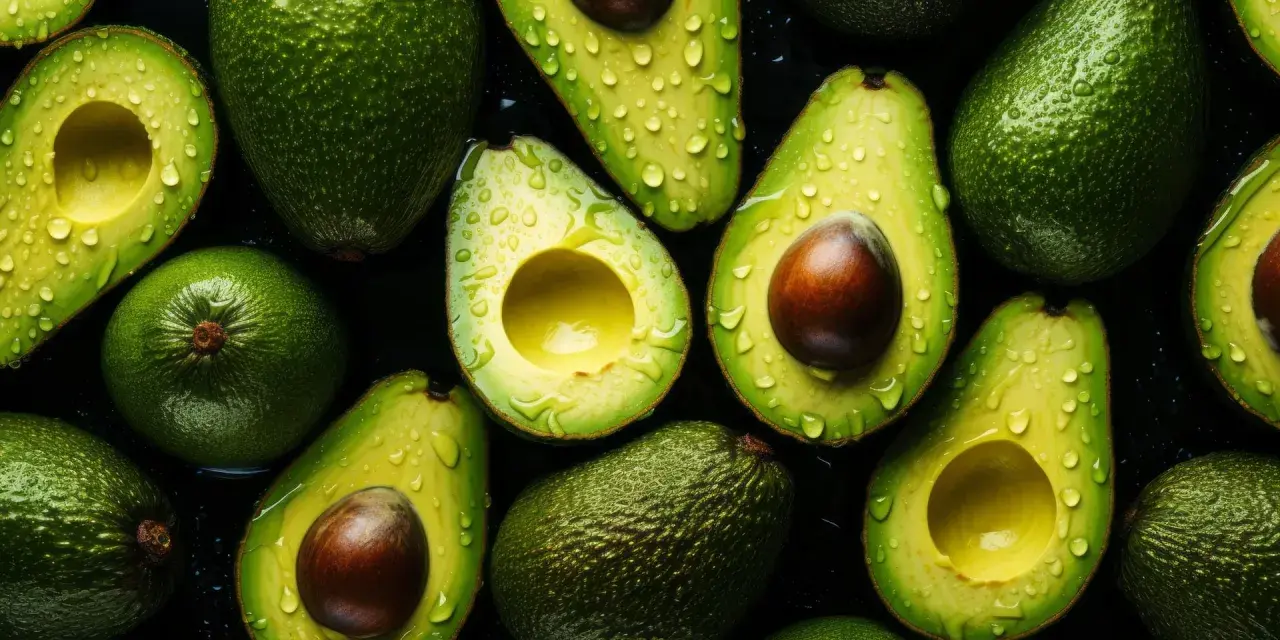 Aguacates frescos y jugosos, cortados y enteros, con gotas de agua, resaltando sus increíbles propiedades nutritivas.