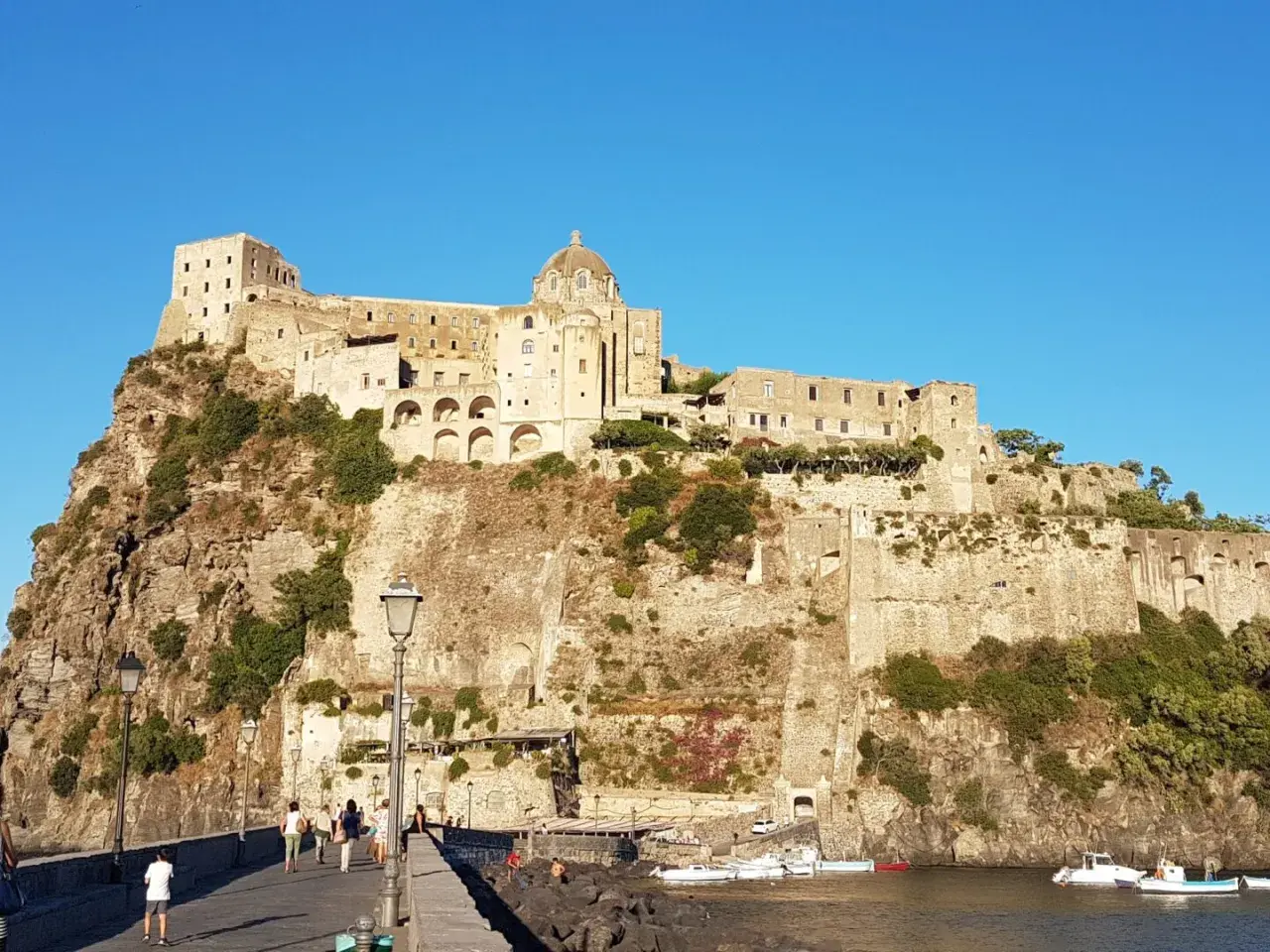 Il Castello Aragonese di Ischia, con i suoi orari e prezzi da scoprire, domina la roccia. Un ponte conduce all'imponente fortezza.