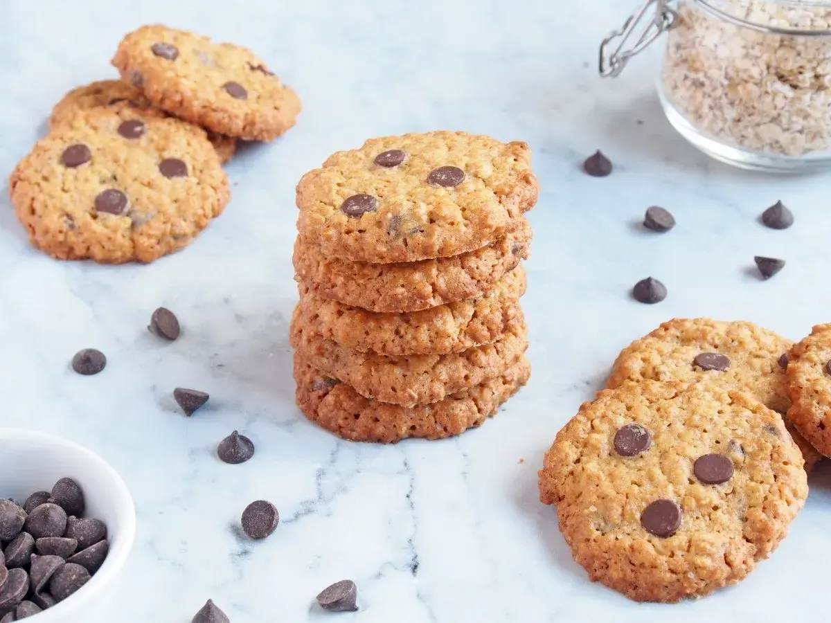 Deliciosas galletas de avena y chocolate, apiladas y esparcidas, con chispas de chocolate y avena en un frasco.