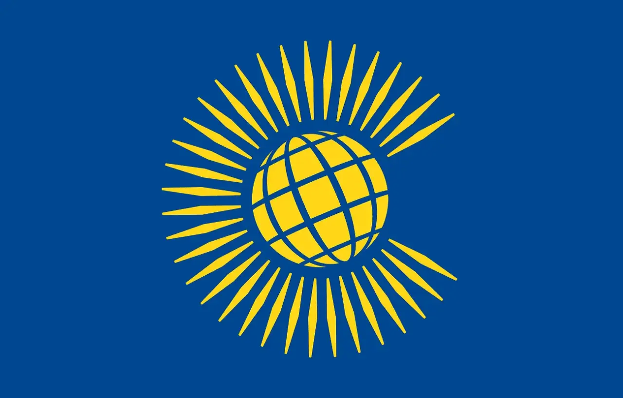 Bandera azul con un globo terráqueo amarillo rodeado de rayos amarillos, representando el Commonwealth.