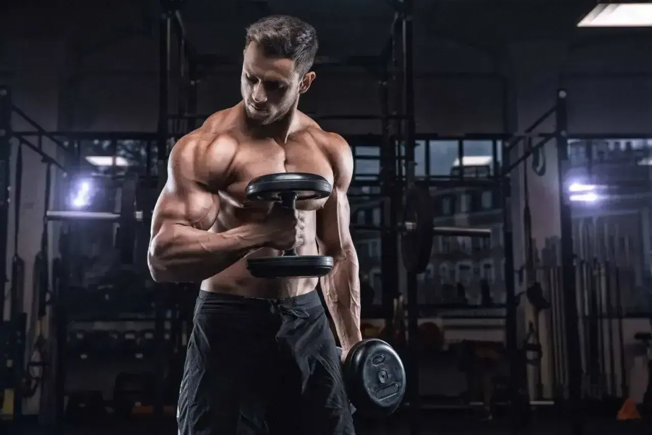 Mężczyzna ćwiczy biceps z hantlami. Ile serii na biceps w tygodniu? To pytanie zadaje sobie wielu trenujących.