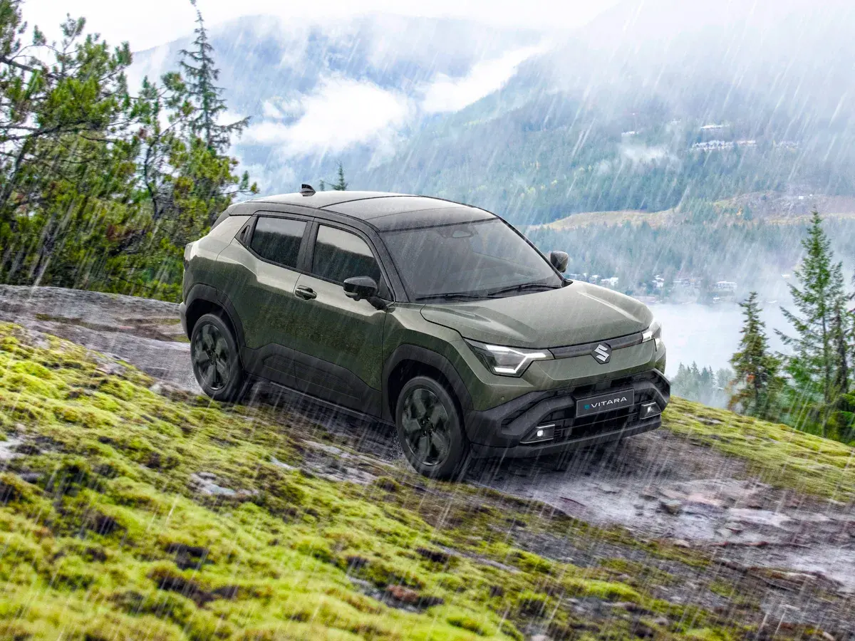 Grön Suzuki Vitara med automatisk växellåda kör på en mossig, stenig sluttning i regn.