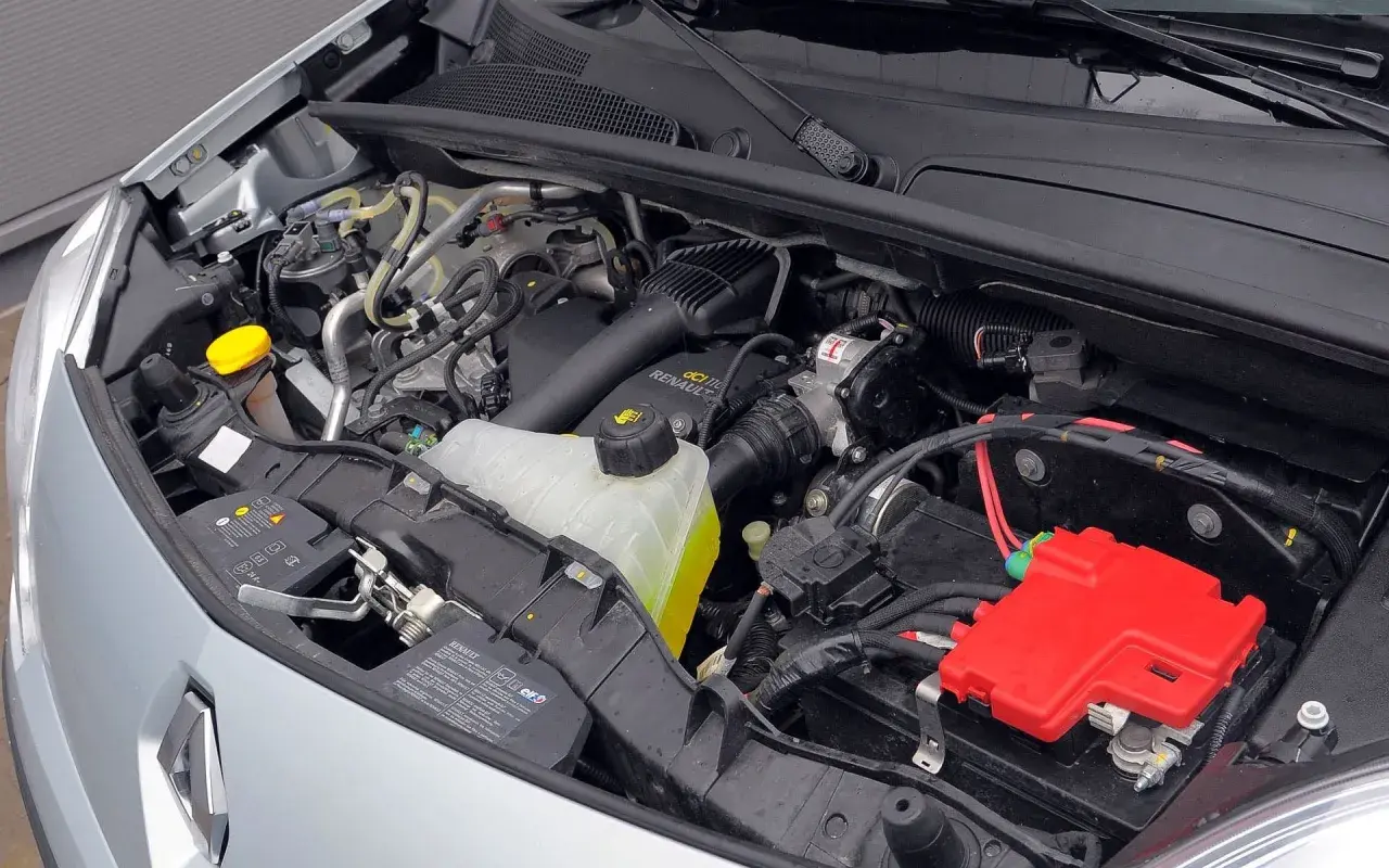 Silnik Renault Kangoo 2 z widocznym zbiorniczkiem płynu chłodniczego, akumulatorem i czerwonymi osłonami.