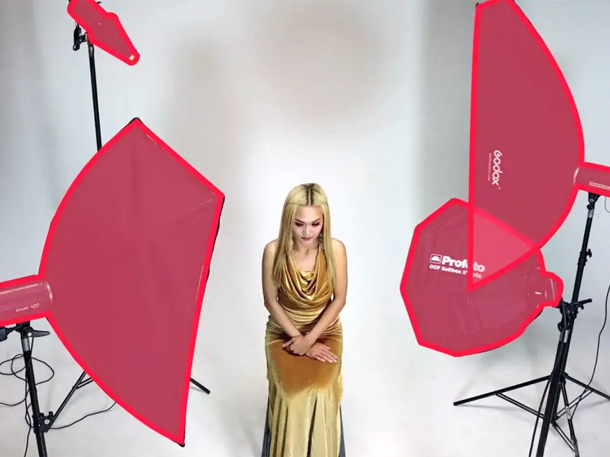 Modelka w złotej sukni, otoczona różnymi rodzajami oświetlenia w fotografii studyjnej.