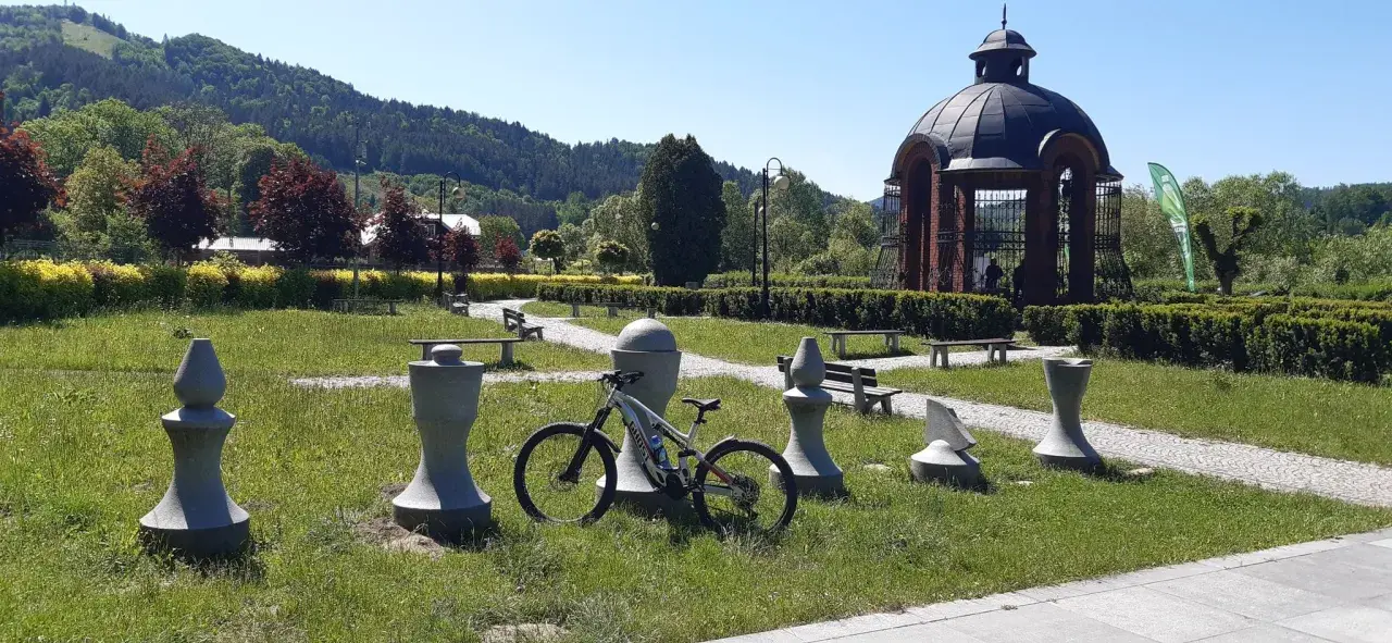 Rower czeka na przygodę na trasie w Muszynie, wśród kamiennych figur i zieleni.
