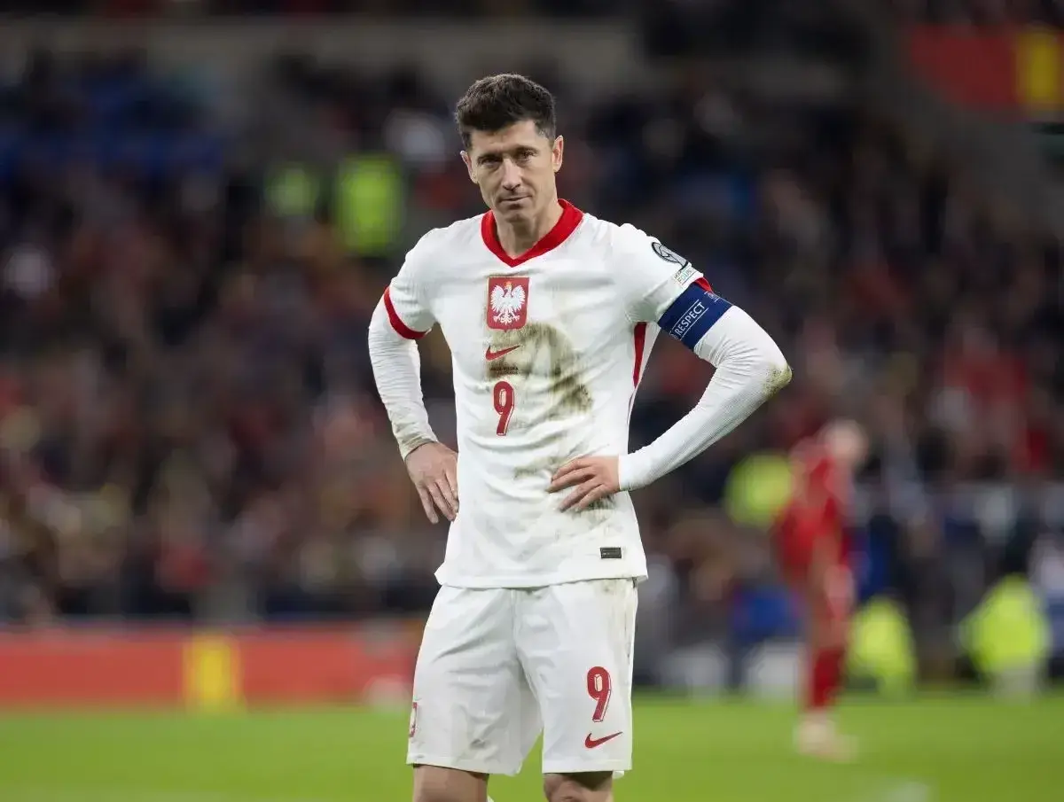 Robert Lewandowski w białej koszulce reprezentacji Polski, z numerem 9 na piersi i spodenkach.