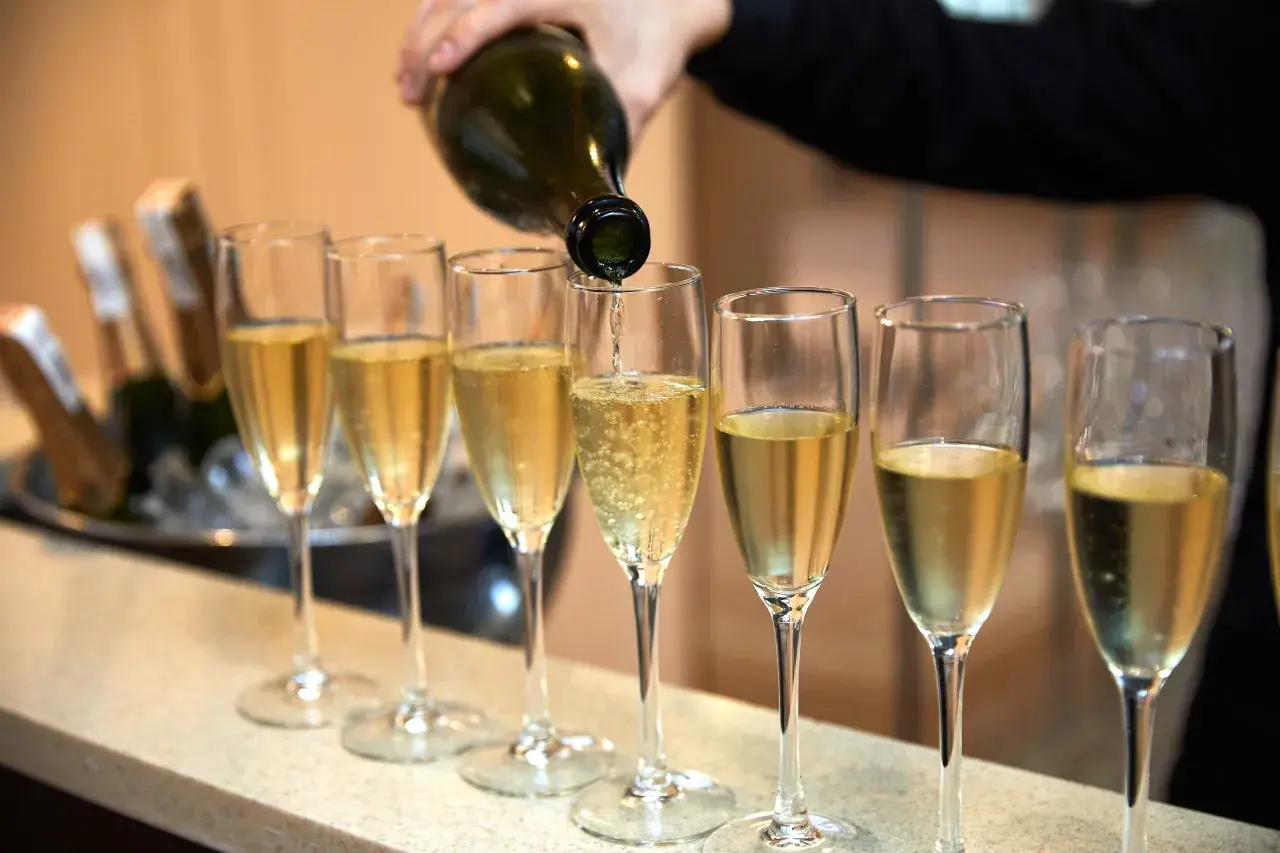 Eine Flasche italienischer Champagner wird in eine Reihe von Gläsern eingeschenkt.