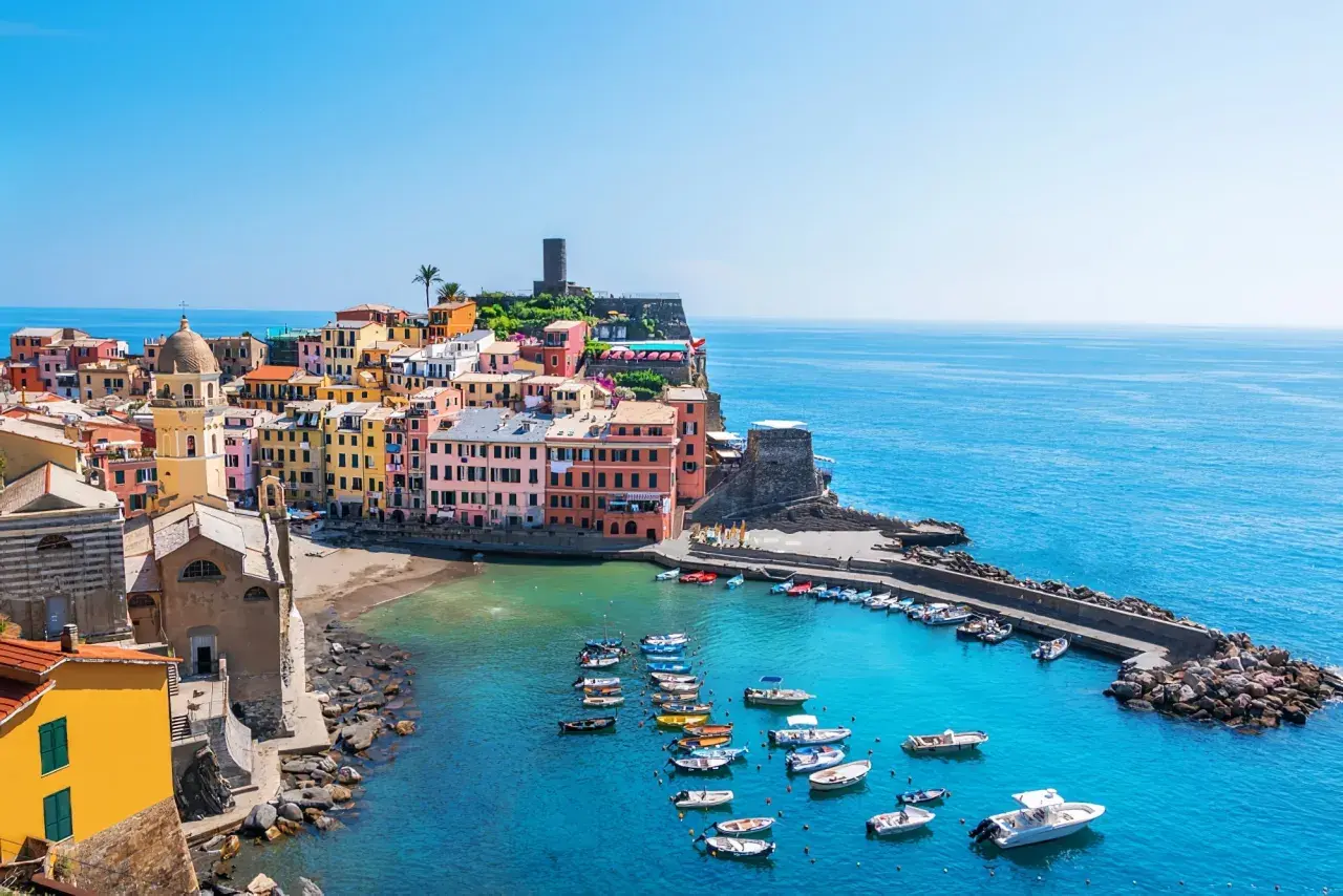 Vue pittoresque des 5 Terres en camping-car : maisons colorées, église, port animé et mer azur.