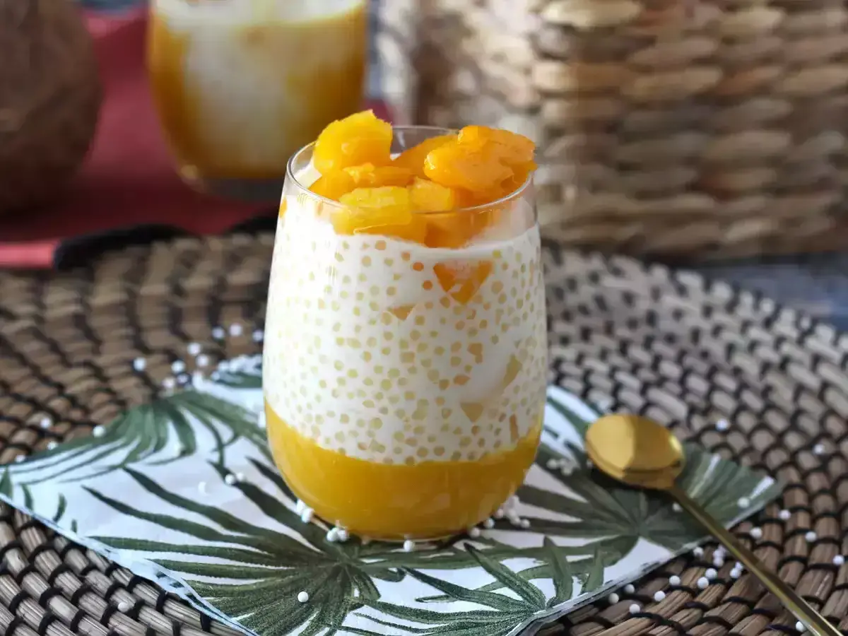 En glas med krämig mango sago, toppad med färsk mango. En tropisk dröm!