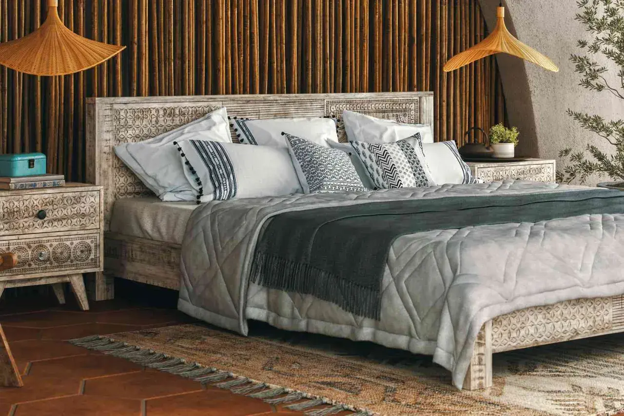 A cozy bedroom with a carved wooden bed, featuring decorative pillow shams. Can you sleep on pillow shams? Yes, they add comfort and style.