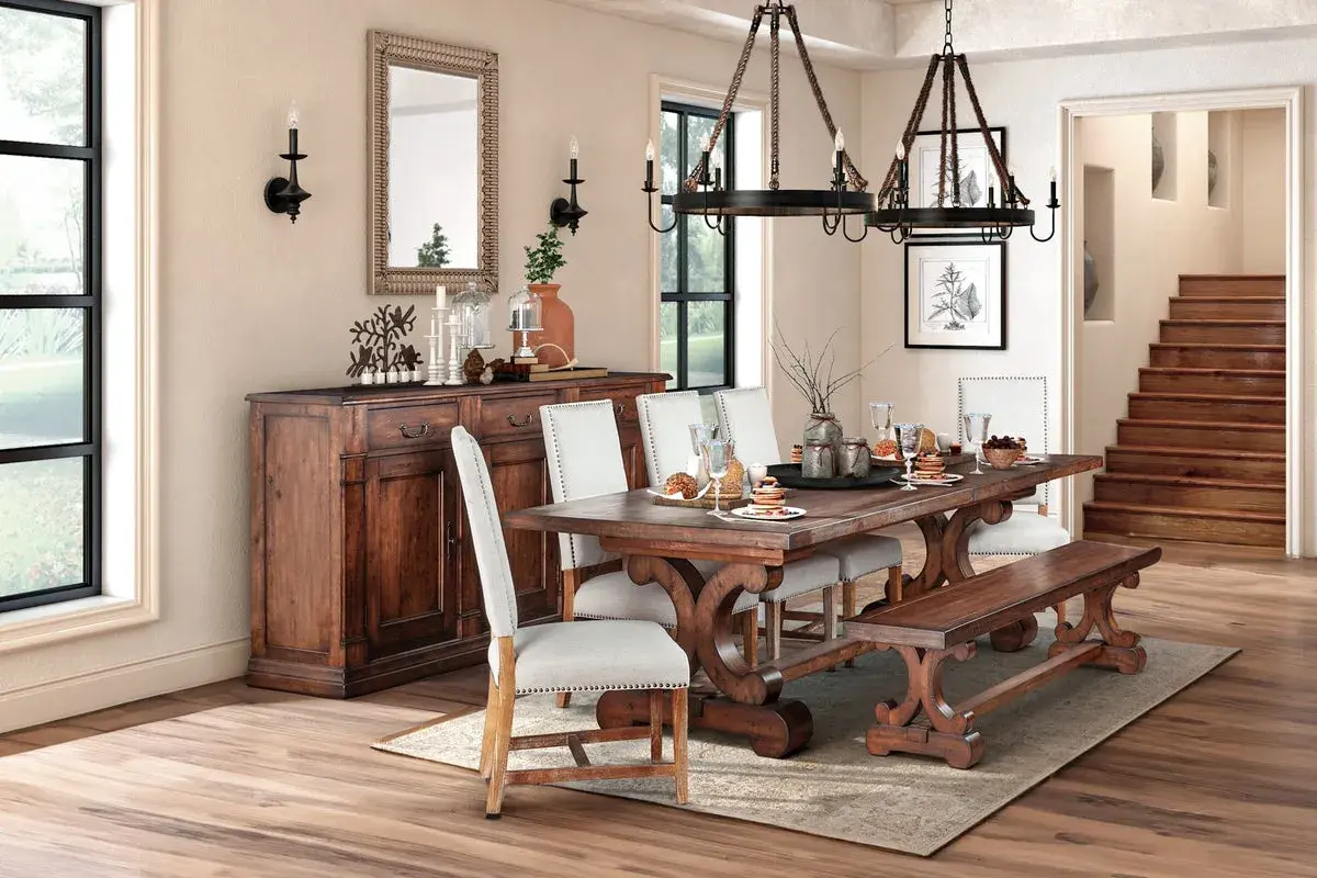 A rustic dining room featuring a dark wood table with ornate legs, upholstered chairs, and a matching bench. This sturdy, beautiful wood is the best wood for kitchen table.