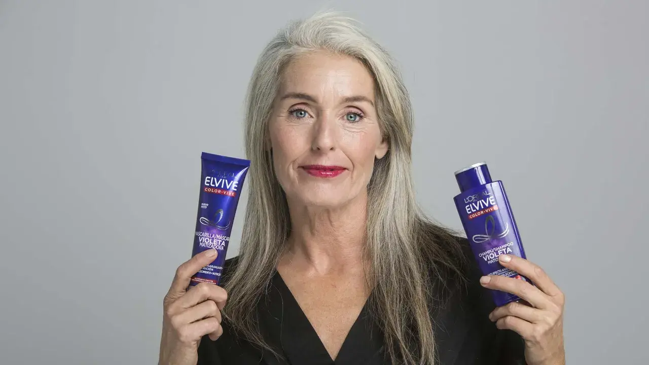 Mujer con cabello gris muestra productos Elvive Color-Vive, ideales como remedios caseros para quitar el amarillo del pelo y matizar.