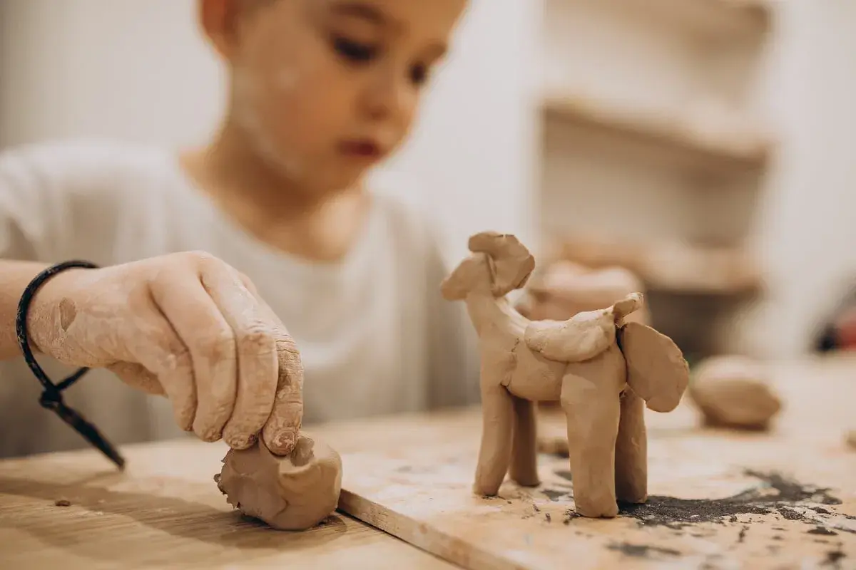 Niño de 2-3 años creando un caballito con arcilla. Divertidas actividades con arcilla para pequeños artistas.