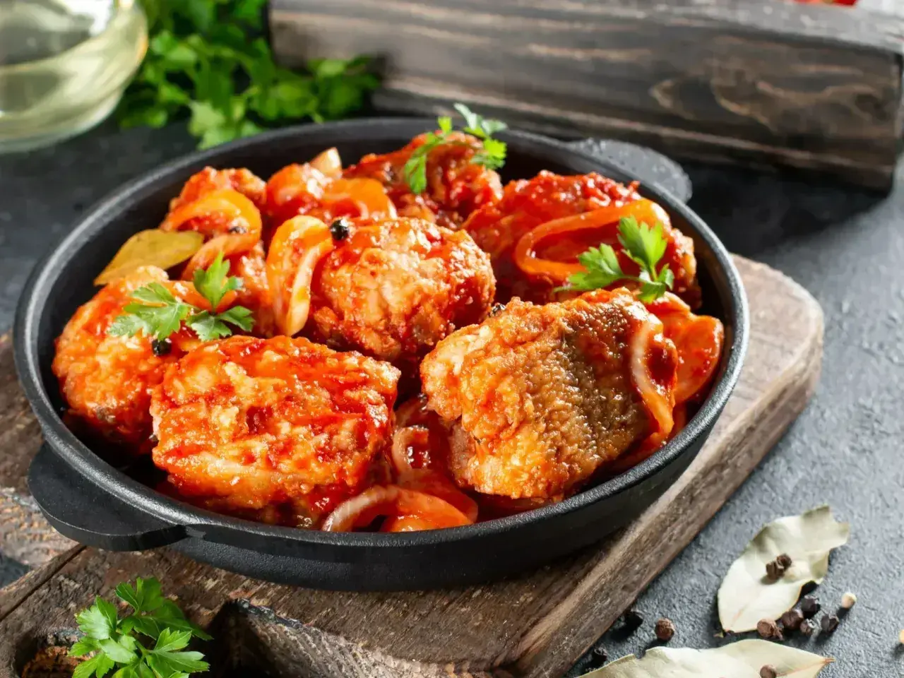 Ryba w sosie pomidorowym z cebulą i natką pietruszki, podana w żeliwnej patelni. Pyszny sos do ryby!