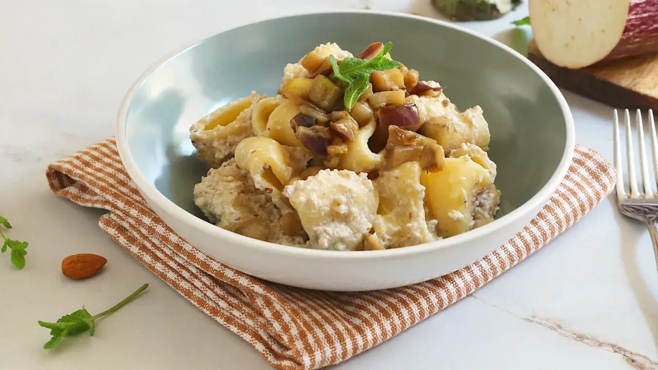 Un piatto invitante di pasta con melanzane in bianco, condita con una crema saporita e guarnita con menta fresca.