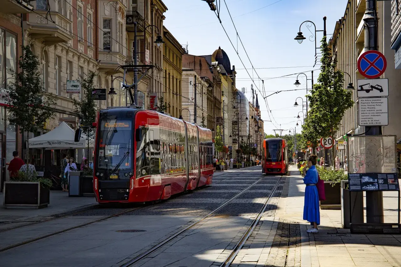 Czerwony tramwaj na ulicy w Katowicach, gdzie można podziwiać wiele atrakcji. Słoneczny dzień zachęca do spacerów.