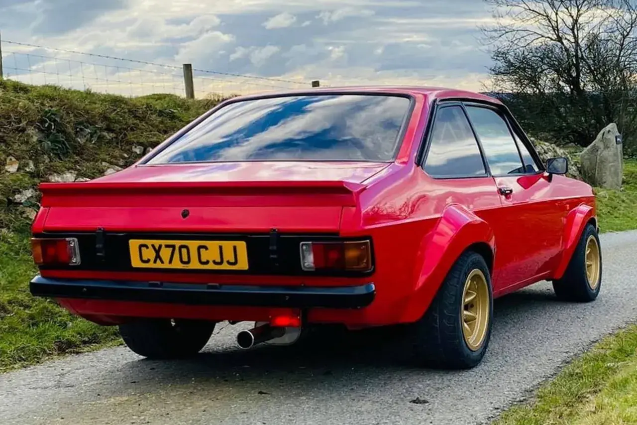 Röd Ford Escort MK2 med breddade skärmar och gul registreringsskylt.