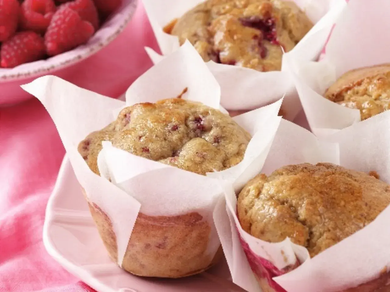 Leckere protein muffins rezept mit Himbeeren, frisch gebacken und auf einem rosa Teller angerichtet.