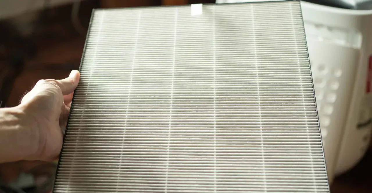 Mano sosteniendo un filtro HEPA. Si te preguntas como limpiar filtro HEPA no lavable, este es el tipo de filtro que debes reemplazar.