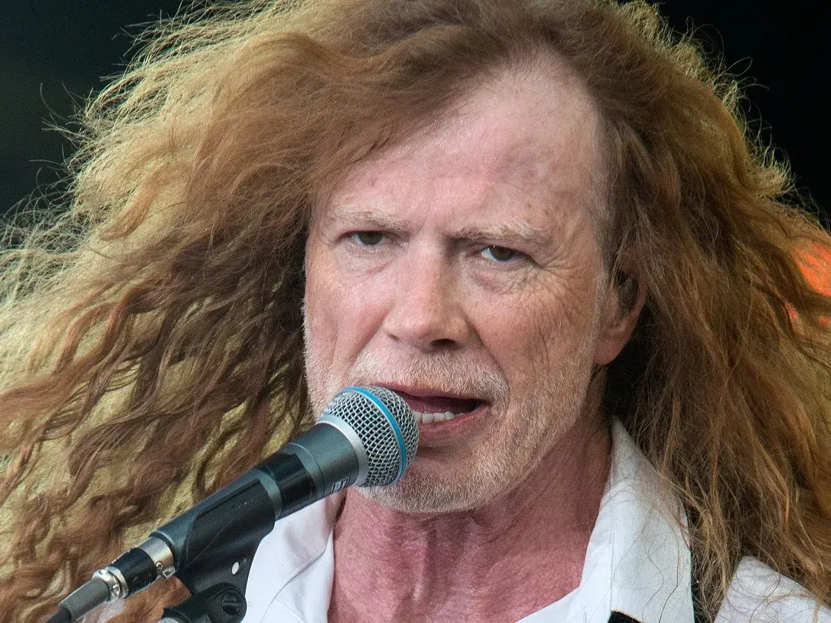 Dave Mustaine young, z burzą rudych włosów i mikrofonem przed ustami, śpiewa na scenie.