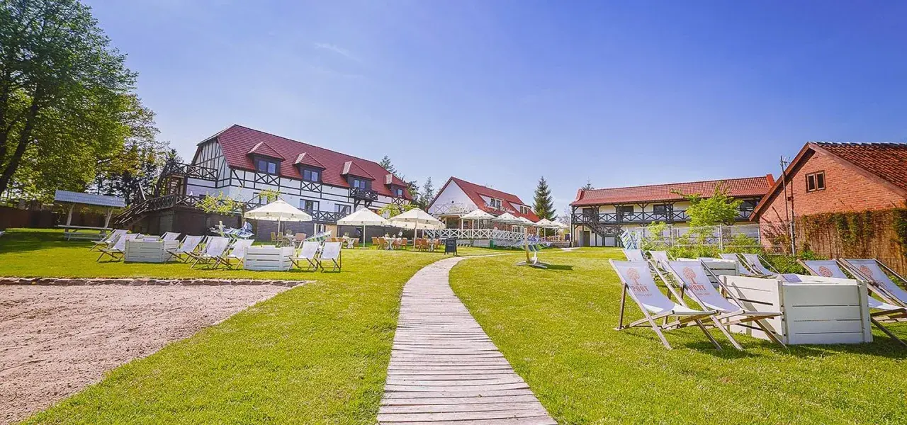Słoneczny dzień na Mazurach. Urokliwe mazurskie miejscowości zapraszają do wypoczynku. Leżaki i parasole czekają na gości przy hotelu.