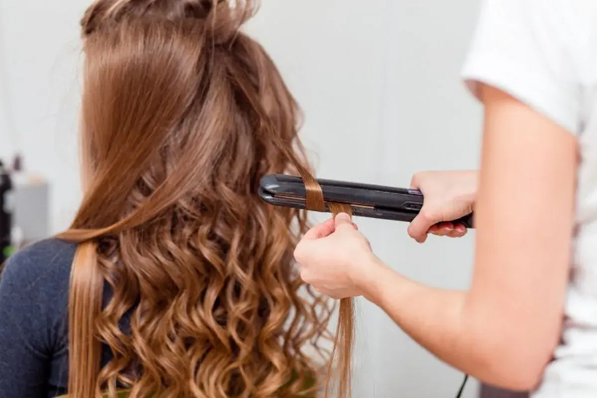 Creando ondas al agua con una plancha. El cabello castaño de una chica se riza, transformándose en suaves ondas.