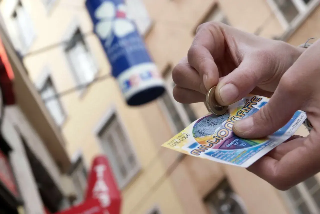 Ręka zdrapuje zdrapkę "Millionaire", krok po kroku po pieniądze. Czy to będzie wygrana pierwszego stopnia?