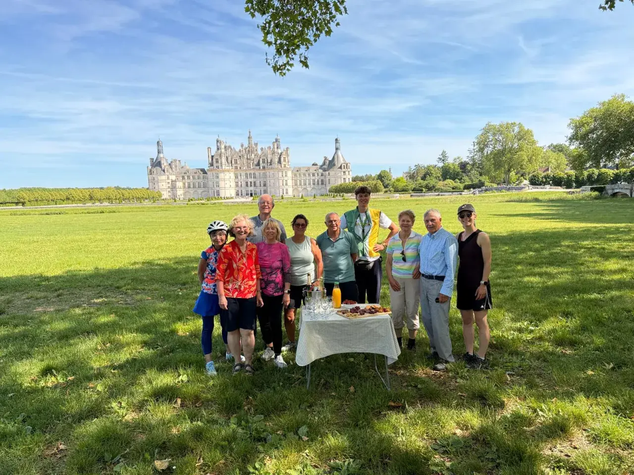 A group enjoys a picnic during their Loire Valley cycling tours, with the magnificent Château de Chambord in the background.