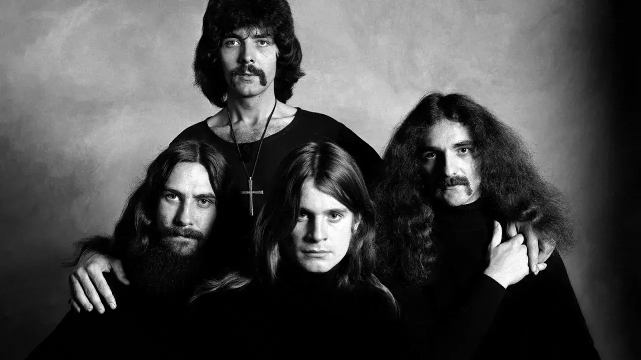 Czterech członków zespołu Black Sabbath, twórców kultowych utworów, pozuje do czarno-białego zdjęcia.