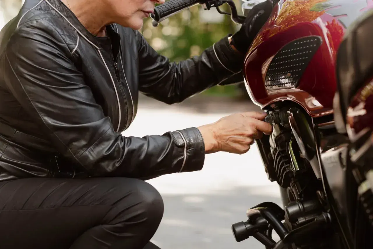 Kobieta w skórzanej kurtce sprawdza regulator napięcia alternatora w motocyklu.