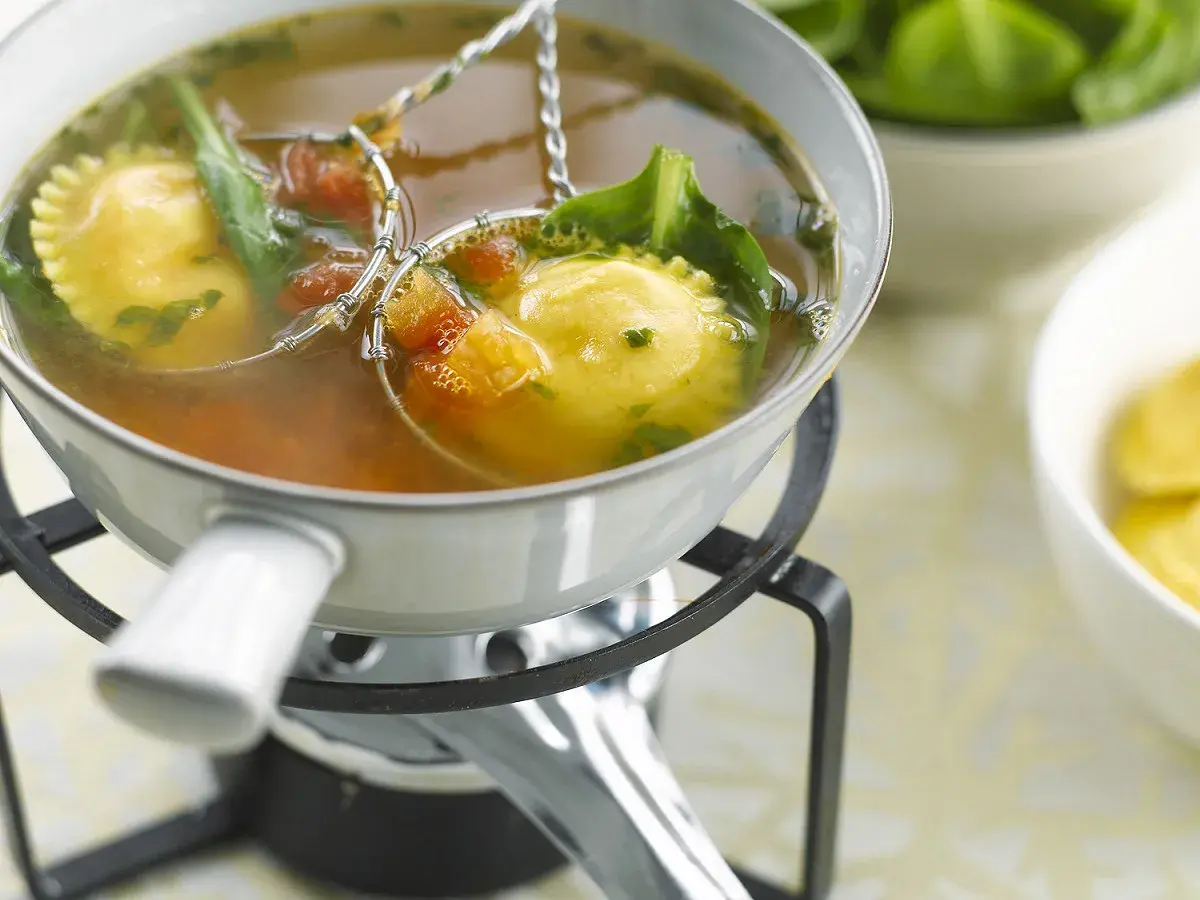 Raviolis dans un bouillon, accompagnés de légumes verts et de tomates. Une délicieuse fondue viande blanche à déguster.