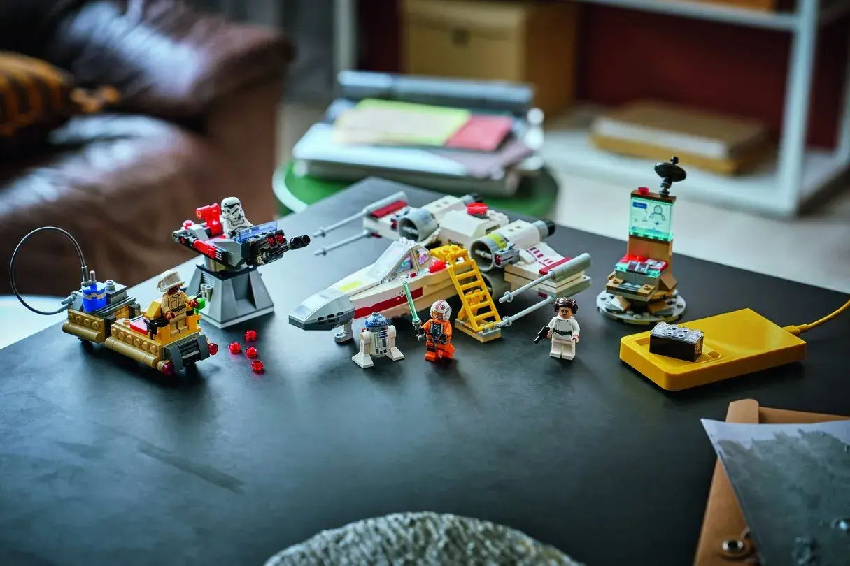 Lego Star Wars X-Wing mit Figuren und einem kleinen, smarten Lego brick auf einer gelben Ladestation.