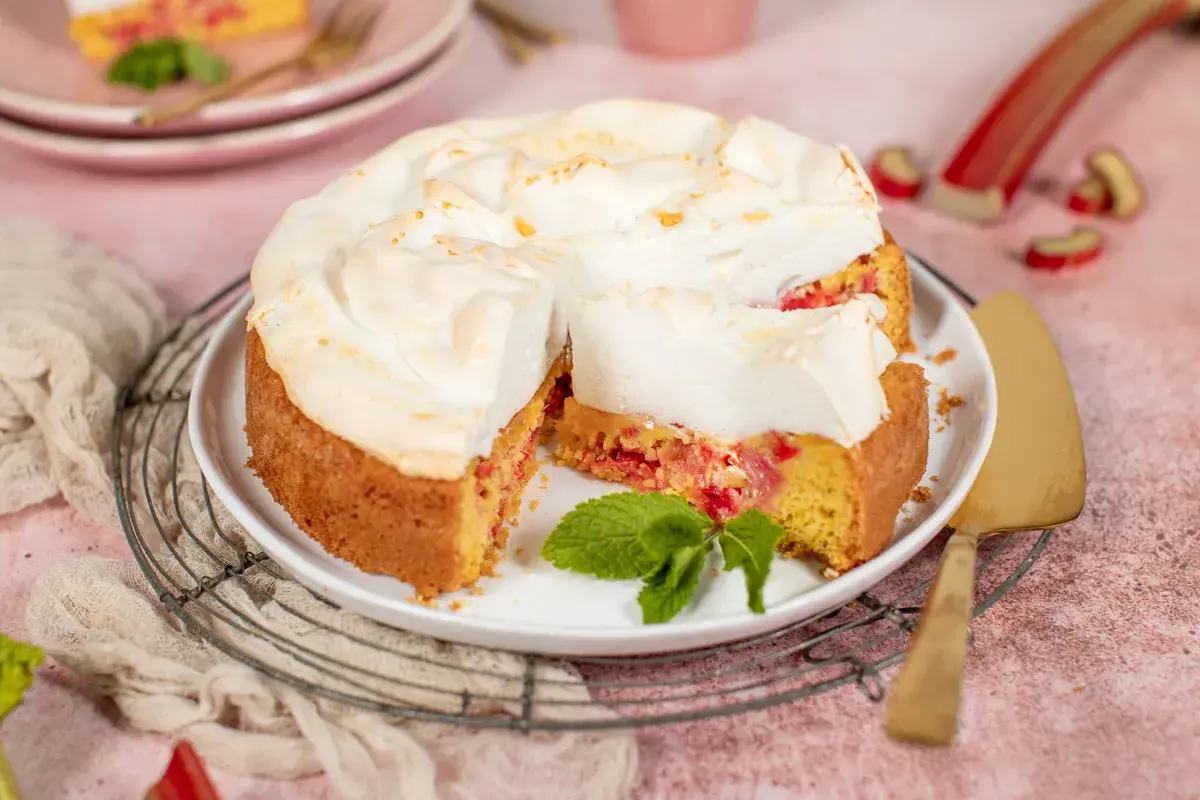 Saftiger Rhabarberkuchen mit luftigem Baiser, garniert mit frischer Minze. Ein Genuss für jeden Kaffeetisch.