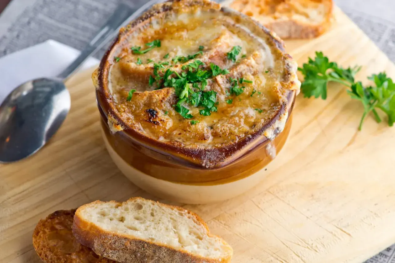 Soupe à l'oignon gratinée, un classique réconfortant. Croutons dorés, fromage fondu et persil frais. Parfait pour une recette maison.