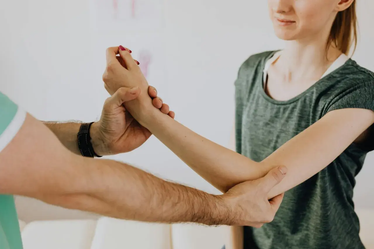 Fizjoterapeuta bada rękę pacjentki, pomagając jej w leczeniu łokcia tenisisty.