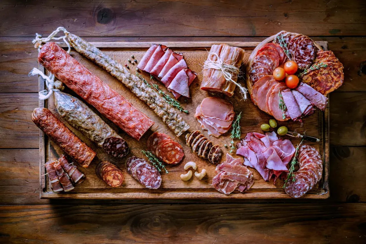 Bei taglieri di salumi e formaggi, un'abbondante selezione di prelibatezze italiane su un tagliere di legno rustico.