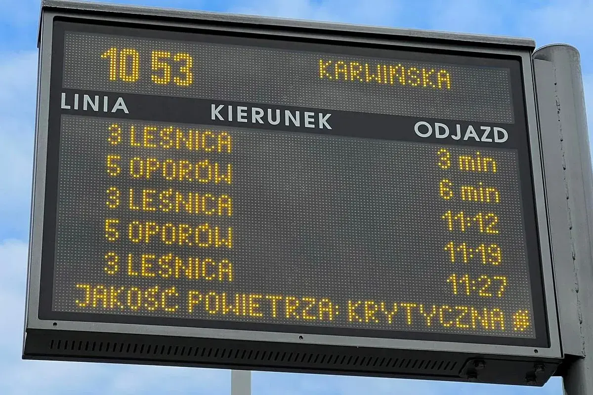 Tablica informacyjna z rozkładem jazdy MPK i informacją o krytycznej jakości powietrza.