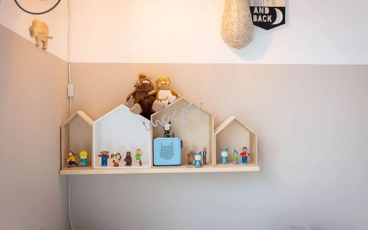 Ein selbstgemachtes Tonie Regal in Hausform, dekoriert mit Figuren und Stofftieren, schafft eine magische Spielzeugwelt.