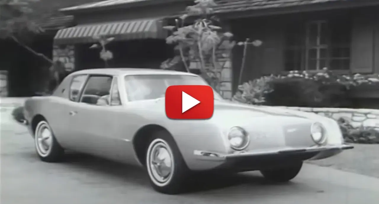 En Studebaker Avanti glider framför ett hus.