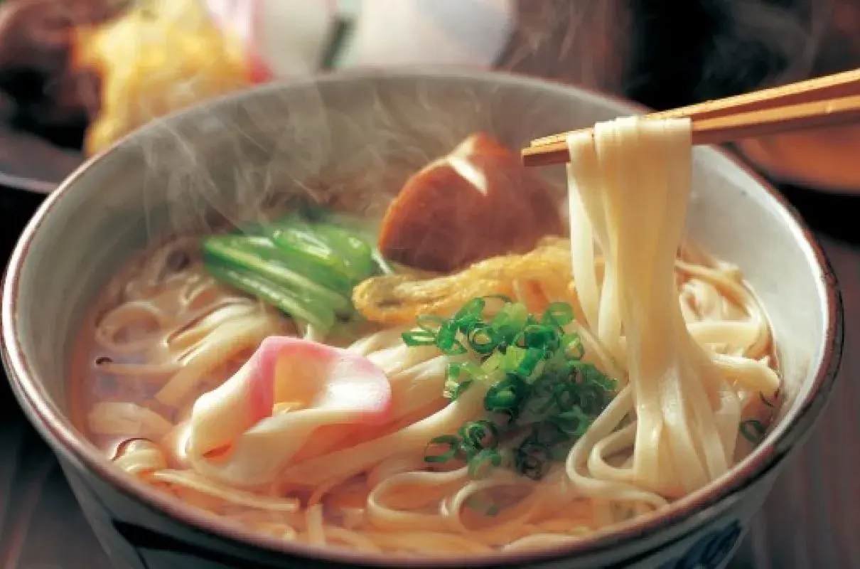 Gorąca zupa z grubym makaronem udon, kawałkami ryby, zieloną cebulką i grzybami. Udon co to? To pyszne danie!