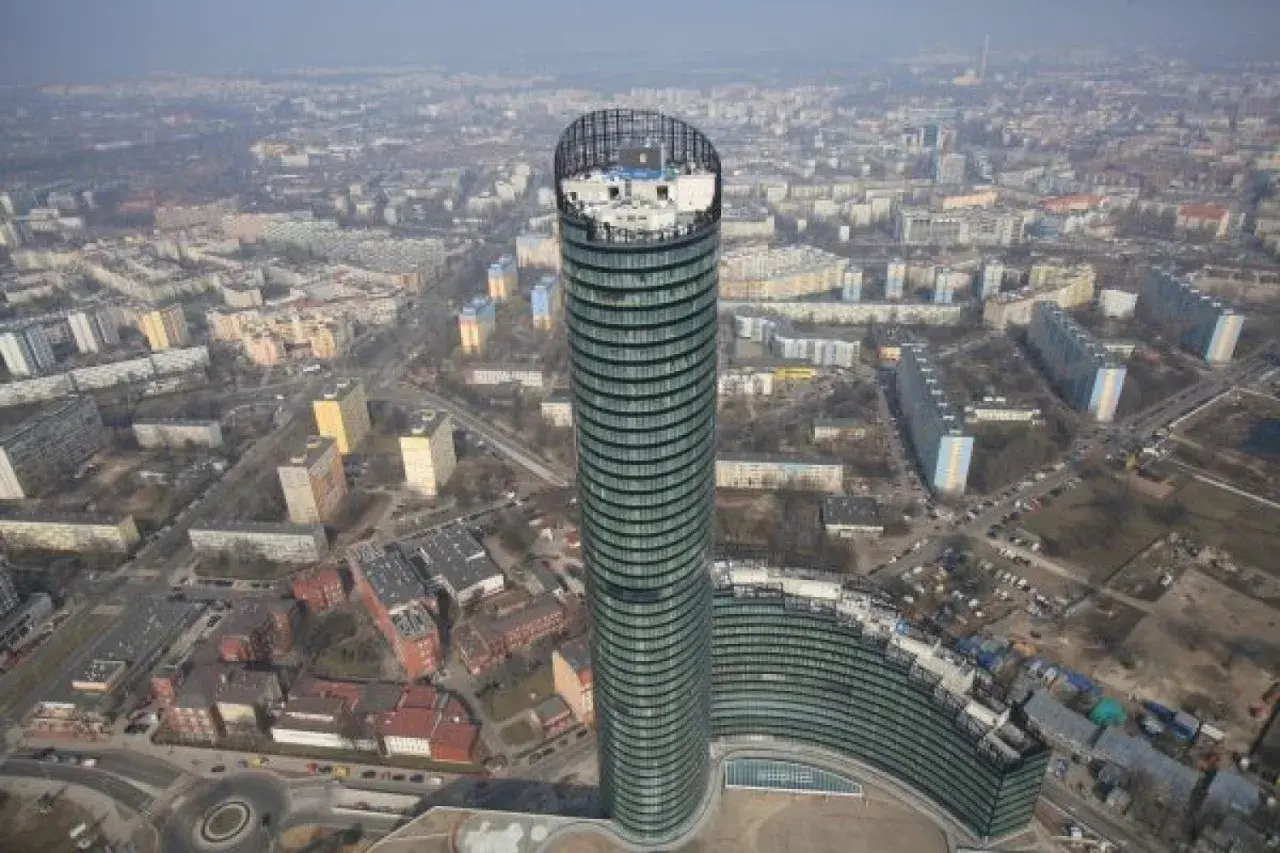 Widok z lotu ptaka na Sky Tower we Wrocławiu, otoczony blokami mieszkalnymi i miejskim krajobrazem.