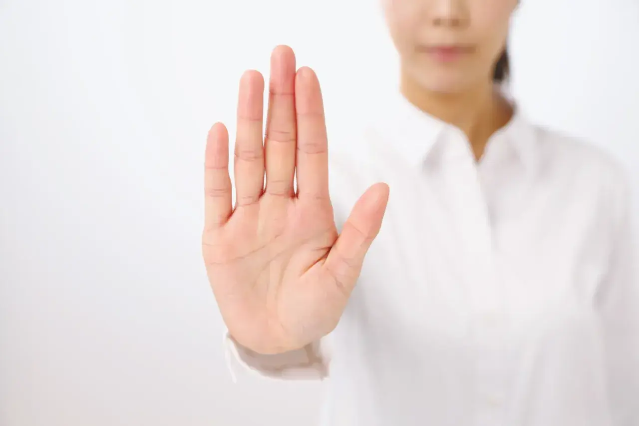 Dłoń uniesiona w geście stop. To symbol asertywności i stawiania granic.